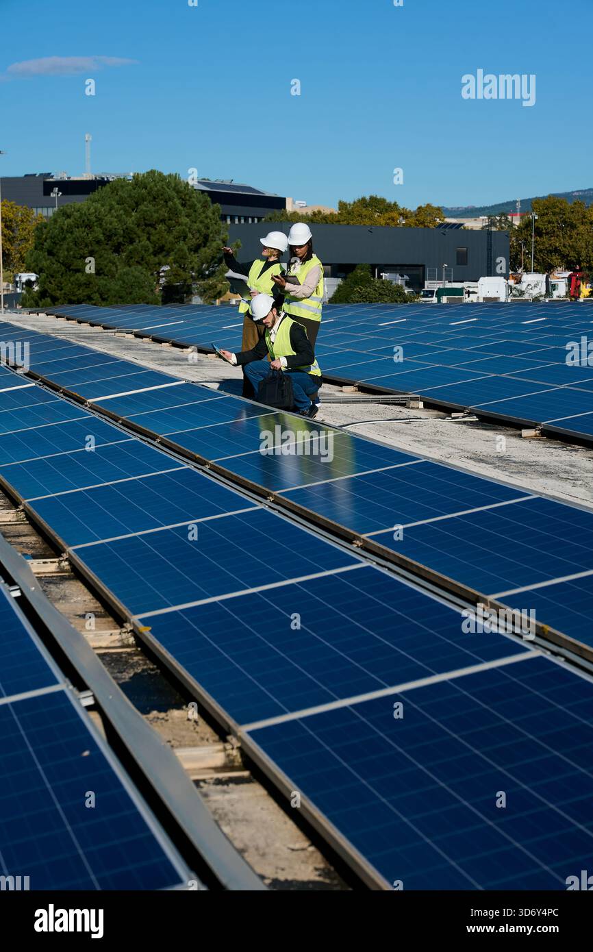 Engineers inspecting rooftop solar panel installation for renewable energy Stock Photo