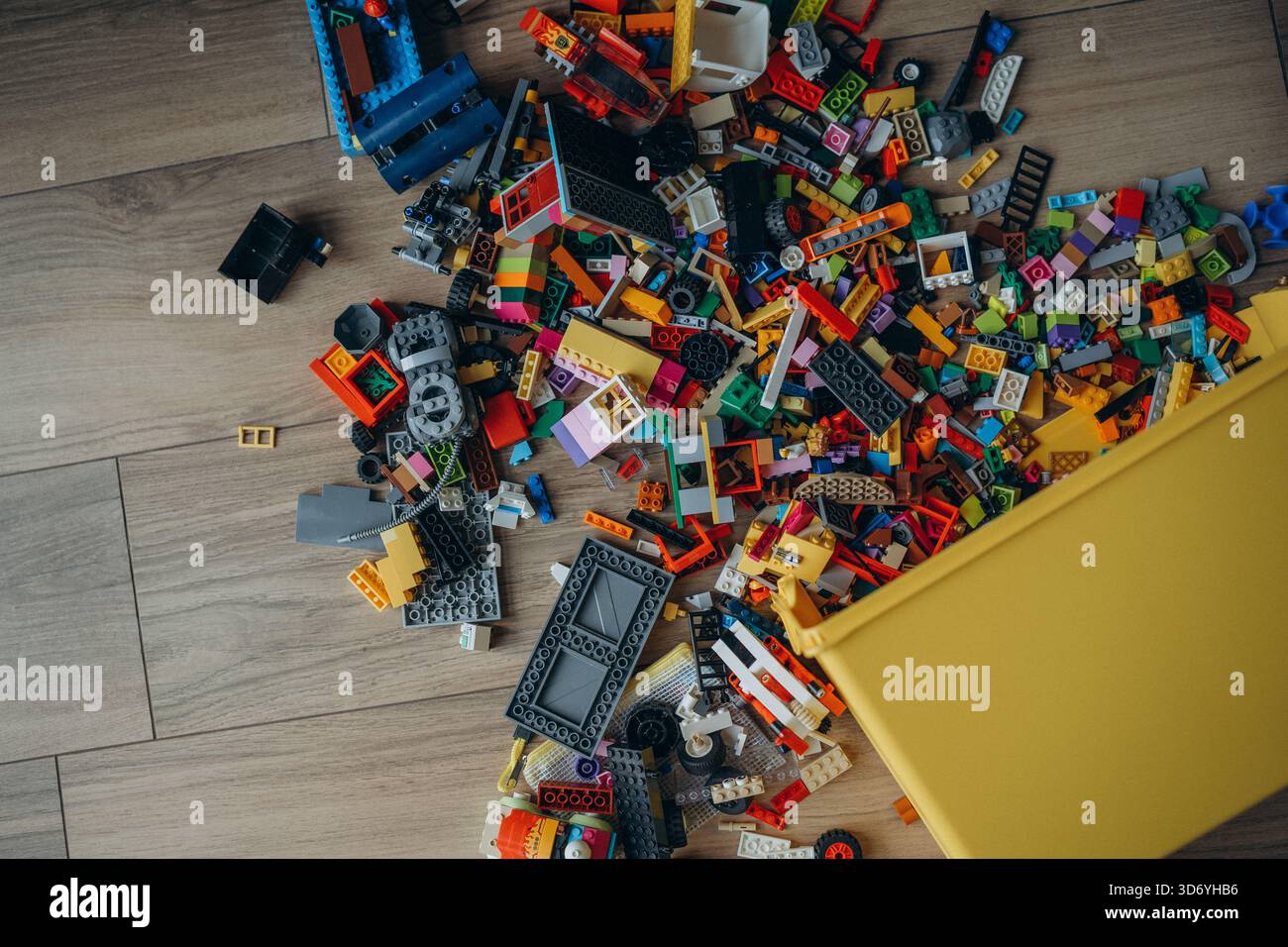 A whole pile of multi-colored Lego bricks spilled out of a yellow box. Photo above. Stock Photo