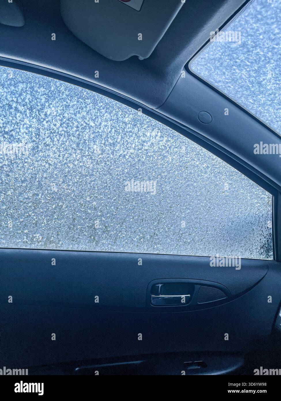 Frozen Car Interior Viewed from Passenger Side. The car's glass is iced over on the outside. - Smartphone Captured Stock Image