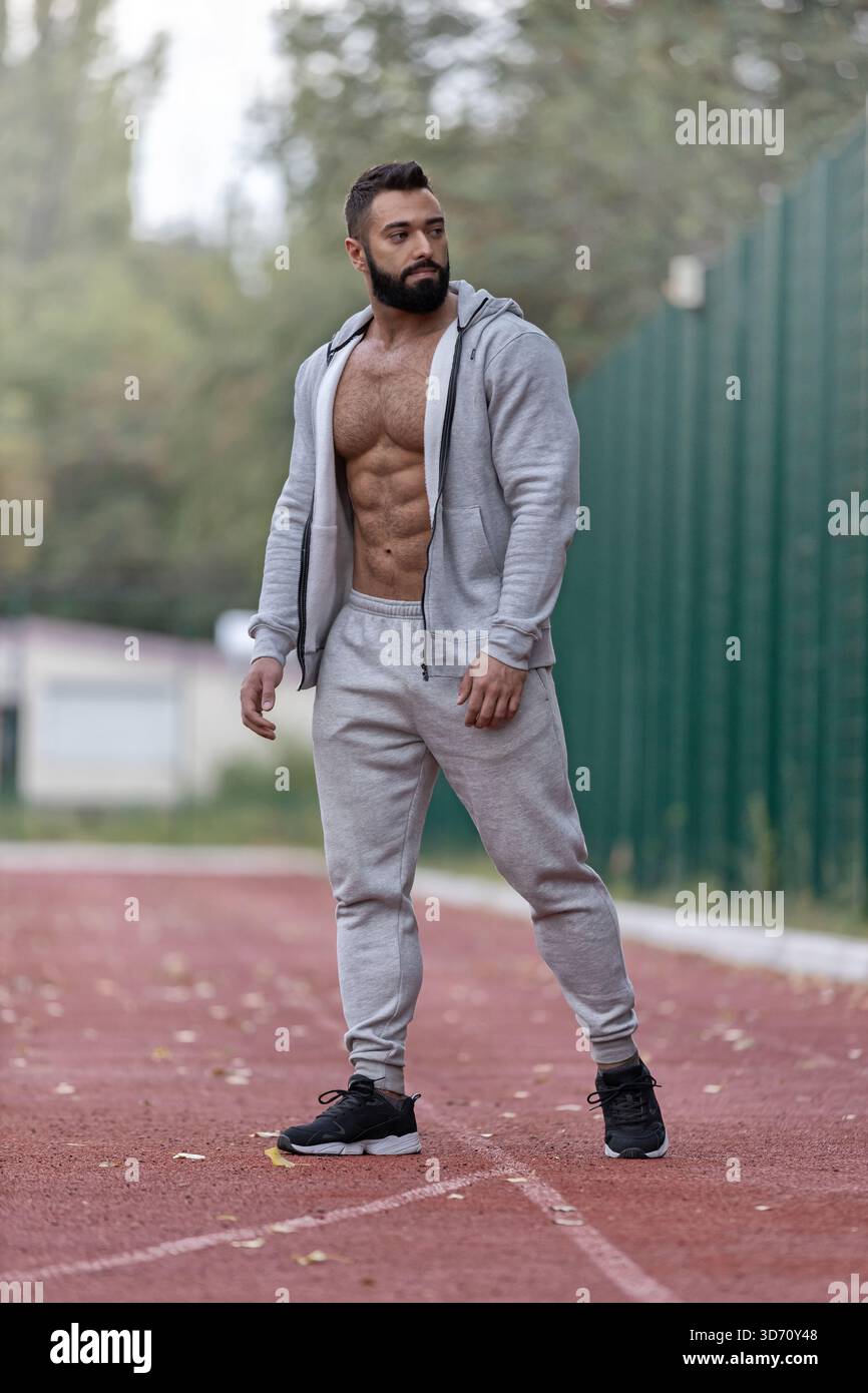 athletic man poses on a sports ground demonstrating his strength and ...