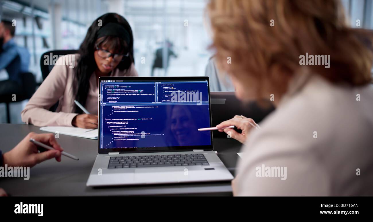 Diverse Team Of Engineers Collaboratively Code Software In Busy Office. Stock Photo