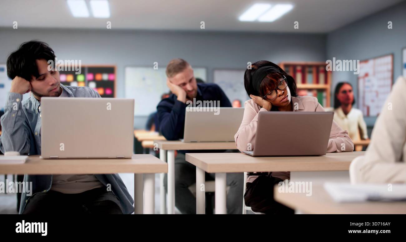 College Students In Classroom Studying With Laptops Look Visibly Bored. Possible Professions: Teacher, Professor Stock Photo