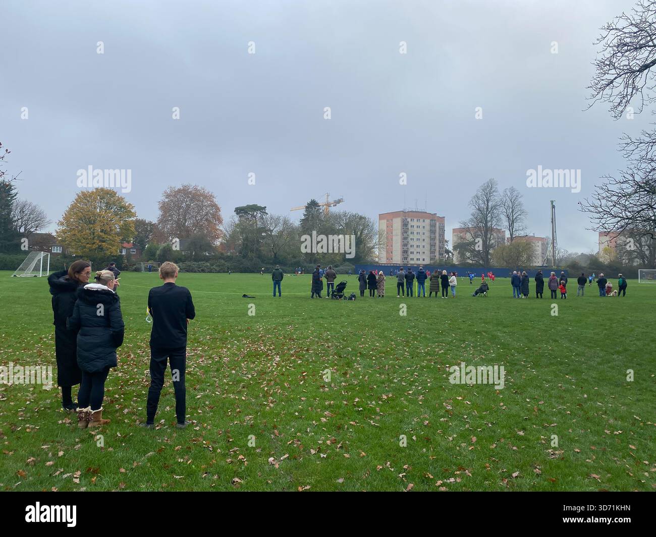 Family and friends stand on the sideline to watch a children's game of football in Windsor, UK - Smartphone Captured Stock Image