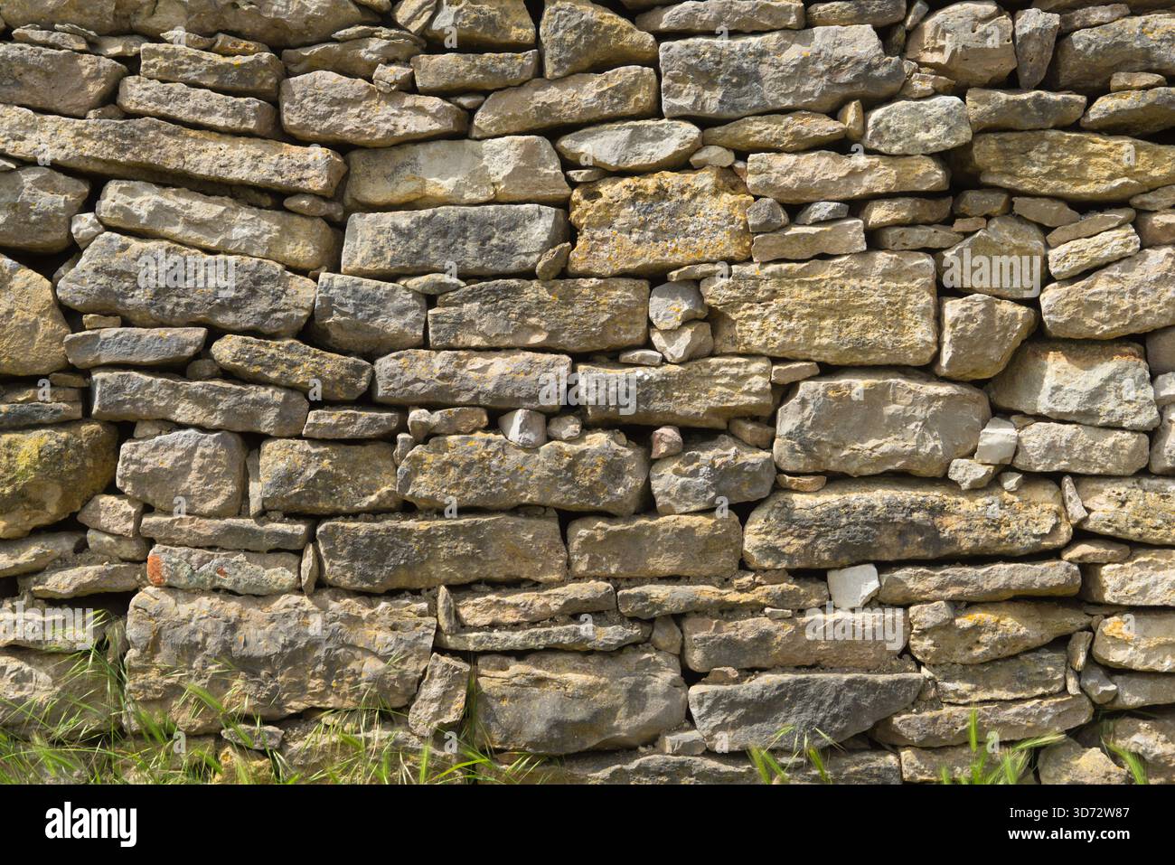Traditional dry-stone wall with weathered rocks in a rural landscape. Stock Photo