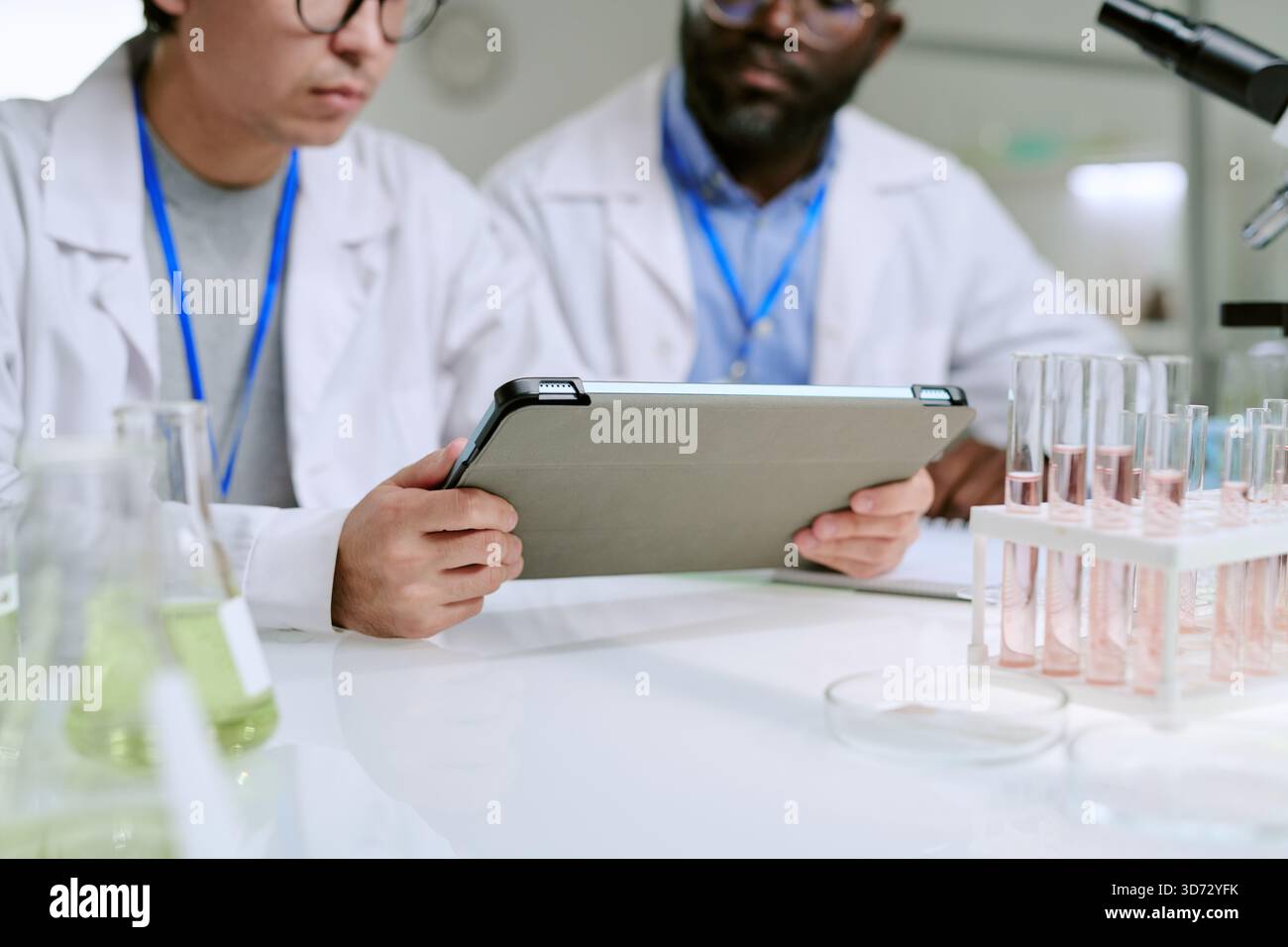 Man and Middle Aged Black Man Analyzing Data on Digital Tablet Stock Photo
