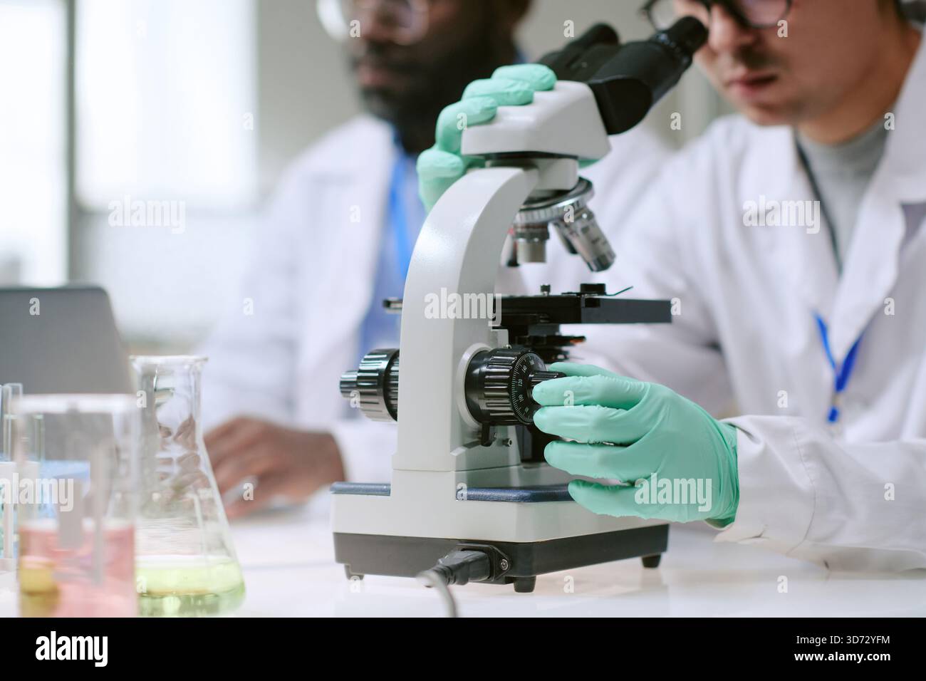 Man and Black Man Using Microscope in Medical Laboratory Stock Photo