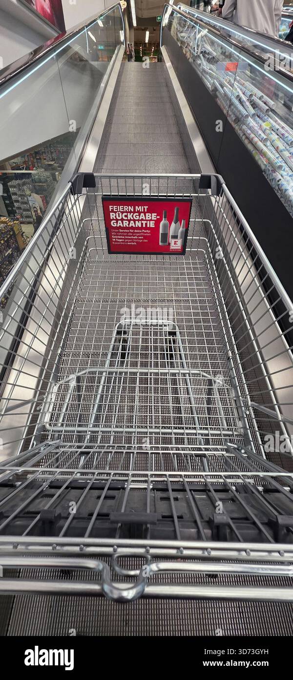 Berlin, Germany - May 10, 2025: Shopping cart is positioned on escalator in supermarket showcasing promotional signage. - Smartphone Captured Stock Image