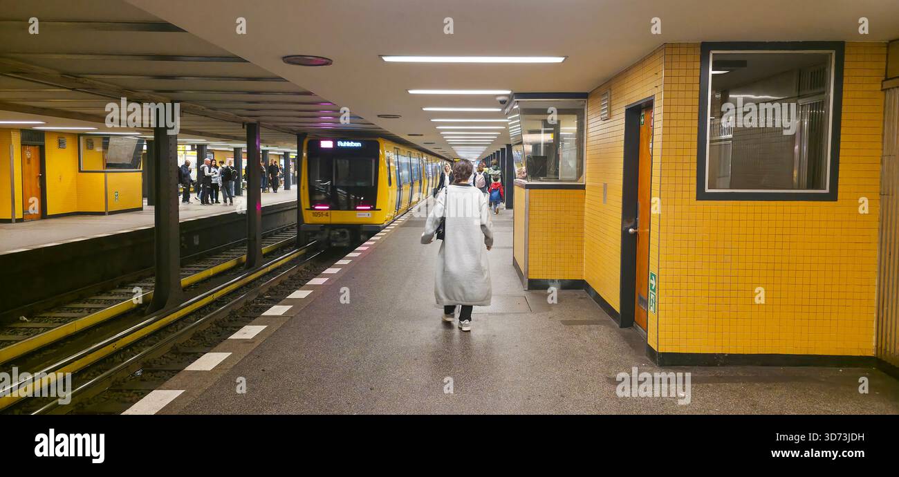Berlin, Germany - July 17, 2025: . Man in long coat is walking along yellow subway station platform with train nearby - Smartphone Captured Stock Image