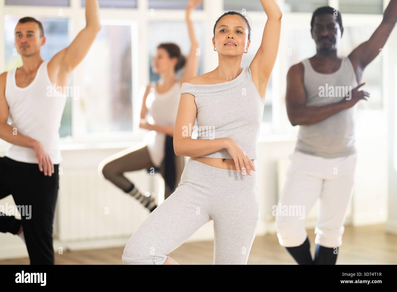 Young Asian woman practicing basic ballet movements at group class Stock Photo