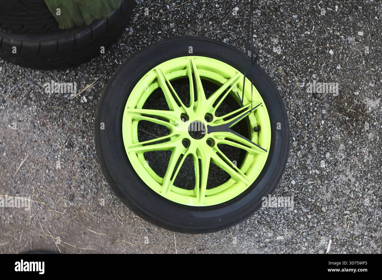 Vibrant neon green car wheel with black tire lying on concrete ...