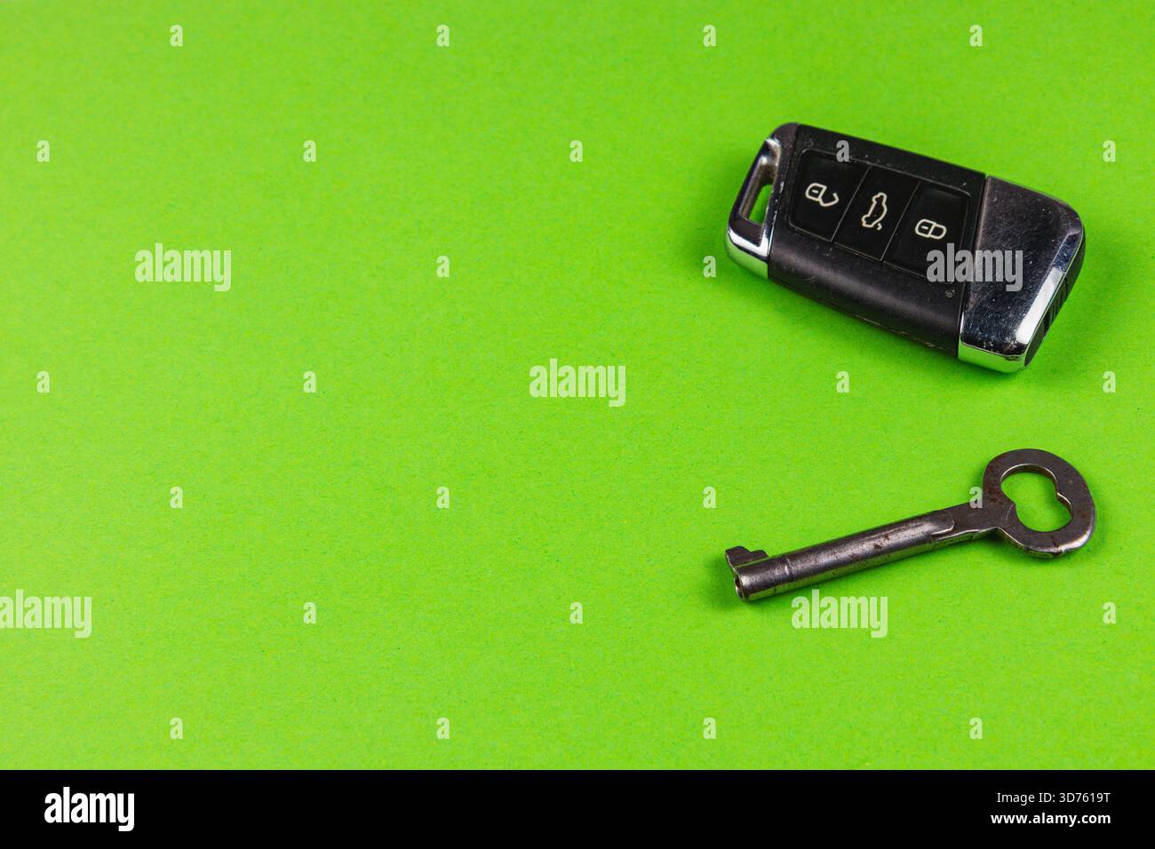 A car key fob and a traditional metal key rest on a vibrant green ...
