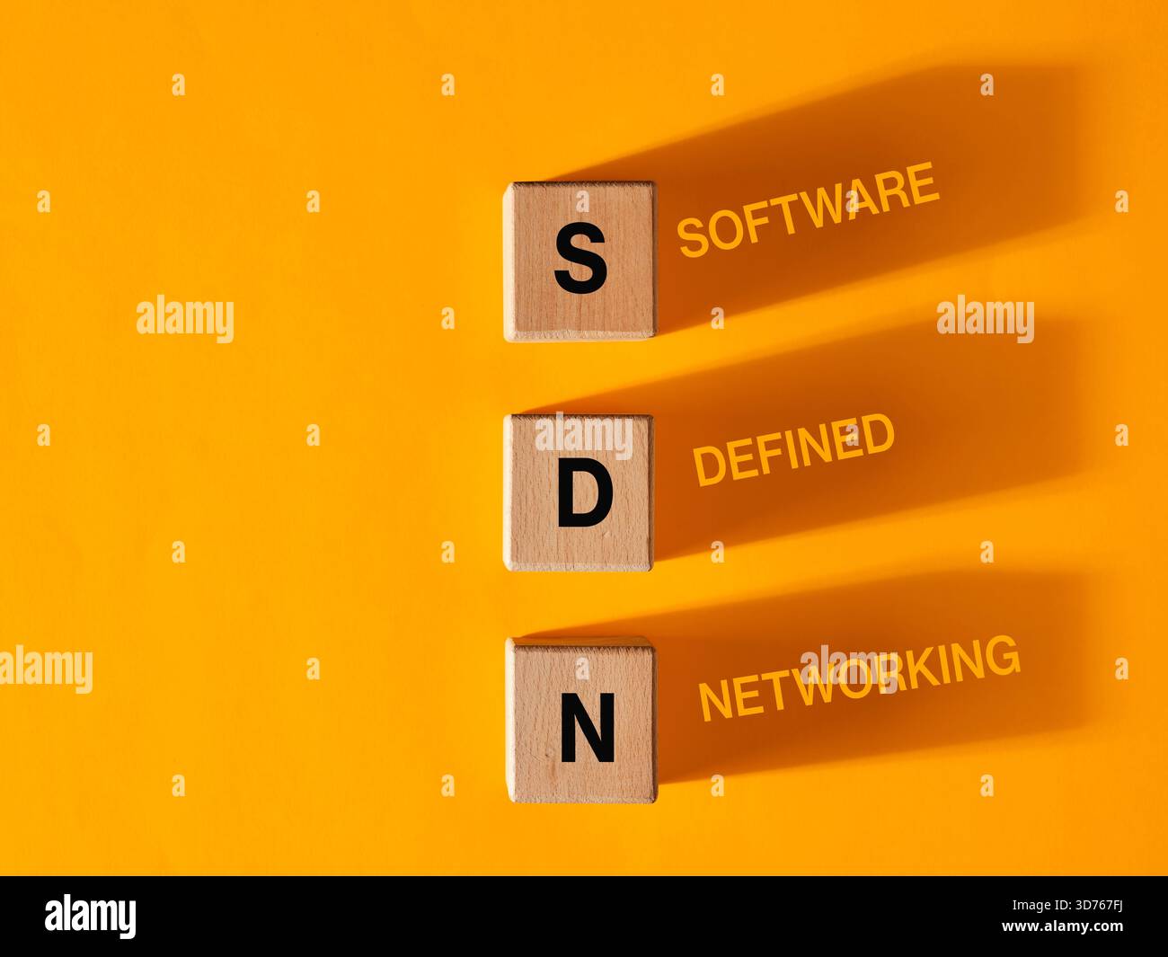Software Defined Networking concept is represented by wooden cubes casting shadows on an orange background Stock Photo