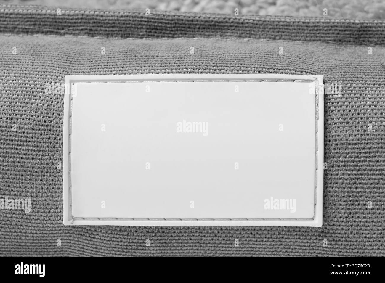 Blank white rubber patch stitched on grey fabric background closeup Stock Photo