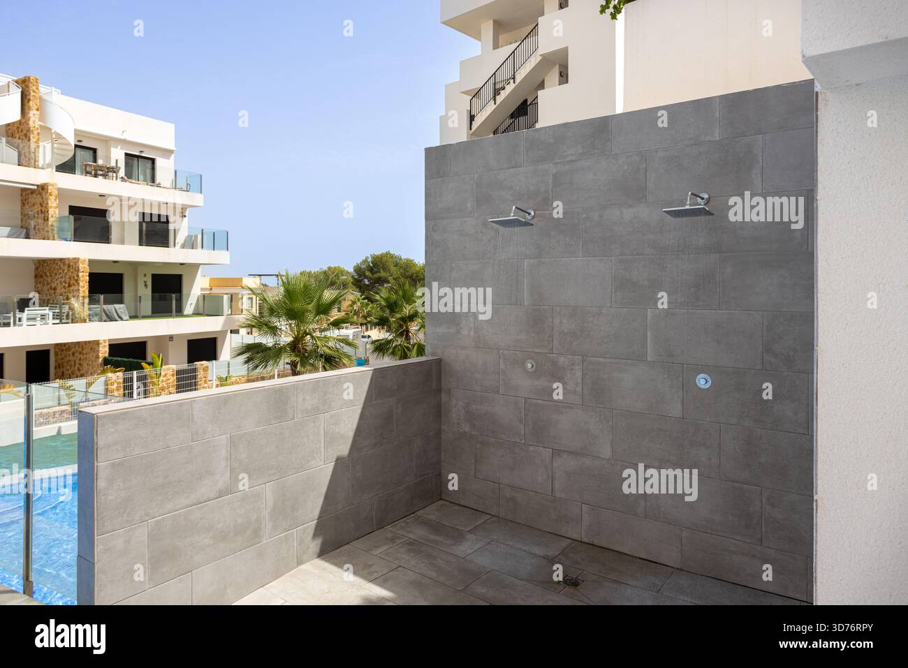 Contemporary outdoor shower space with tiled wall beside apartment