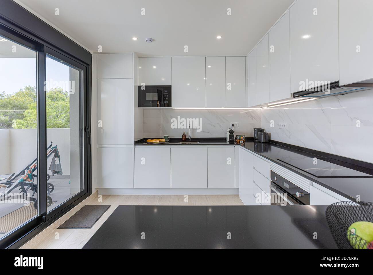 Modern white kitchen with glossy cabinets, built-in appliances, and ...
