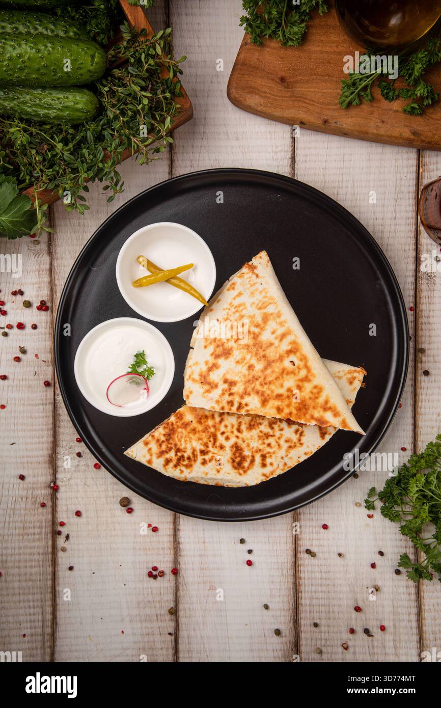 Grilled chicken quesadilla on black plate serving Stock Photo