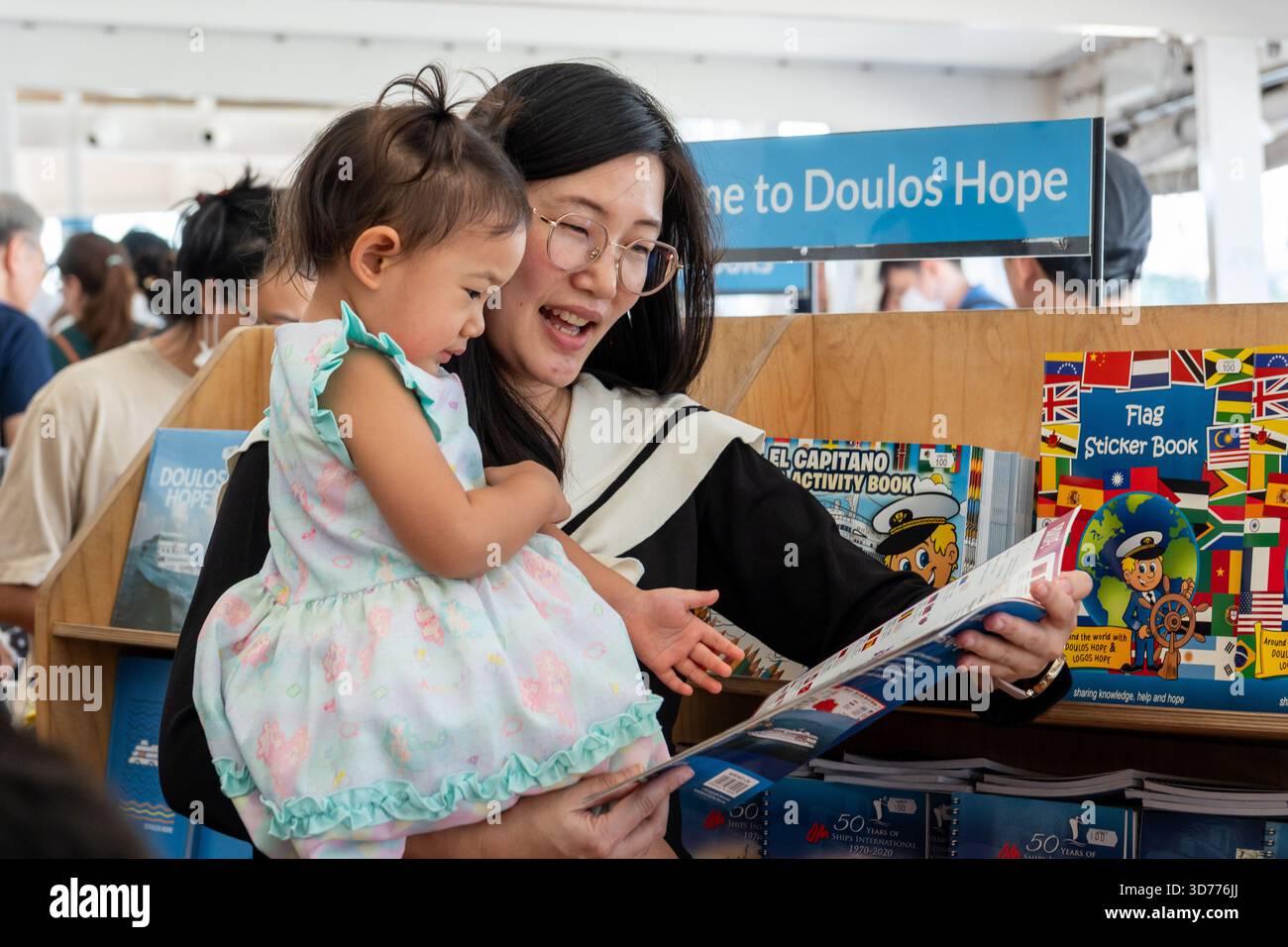 A mother shows a book to her young daughter, at the Doulos Hope ...