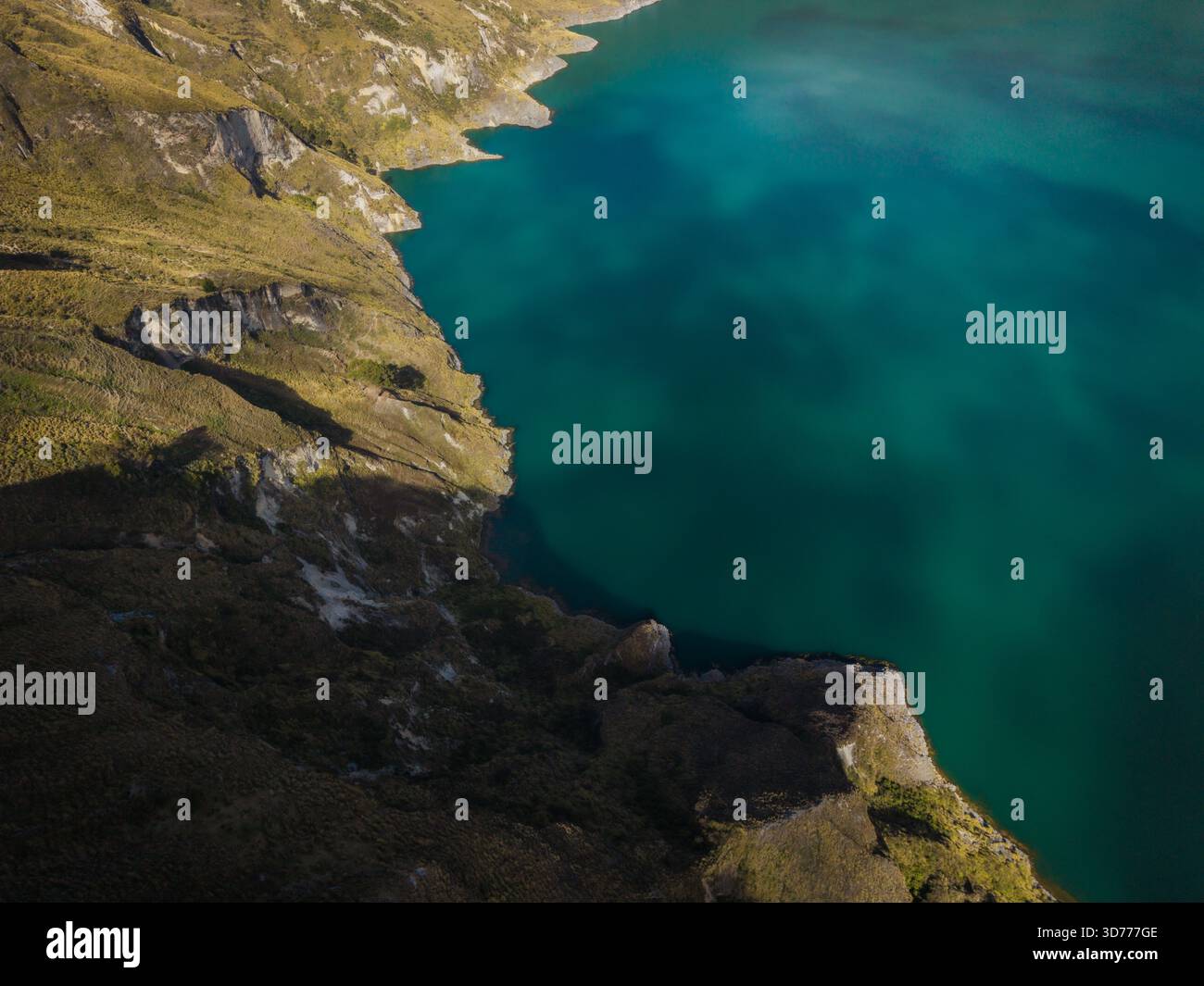Aerial view of the turquoise lake waters meeting the rugged, grassy ...