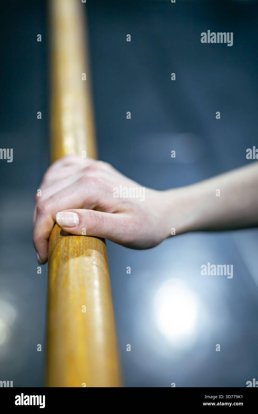 ballerina's hand resting on ballet barre Stock Photo