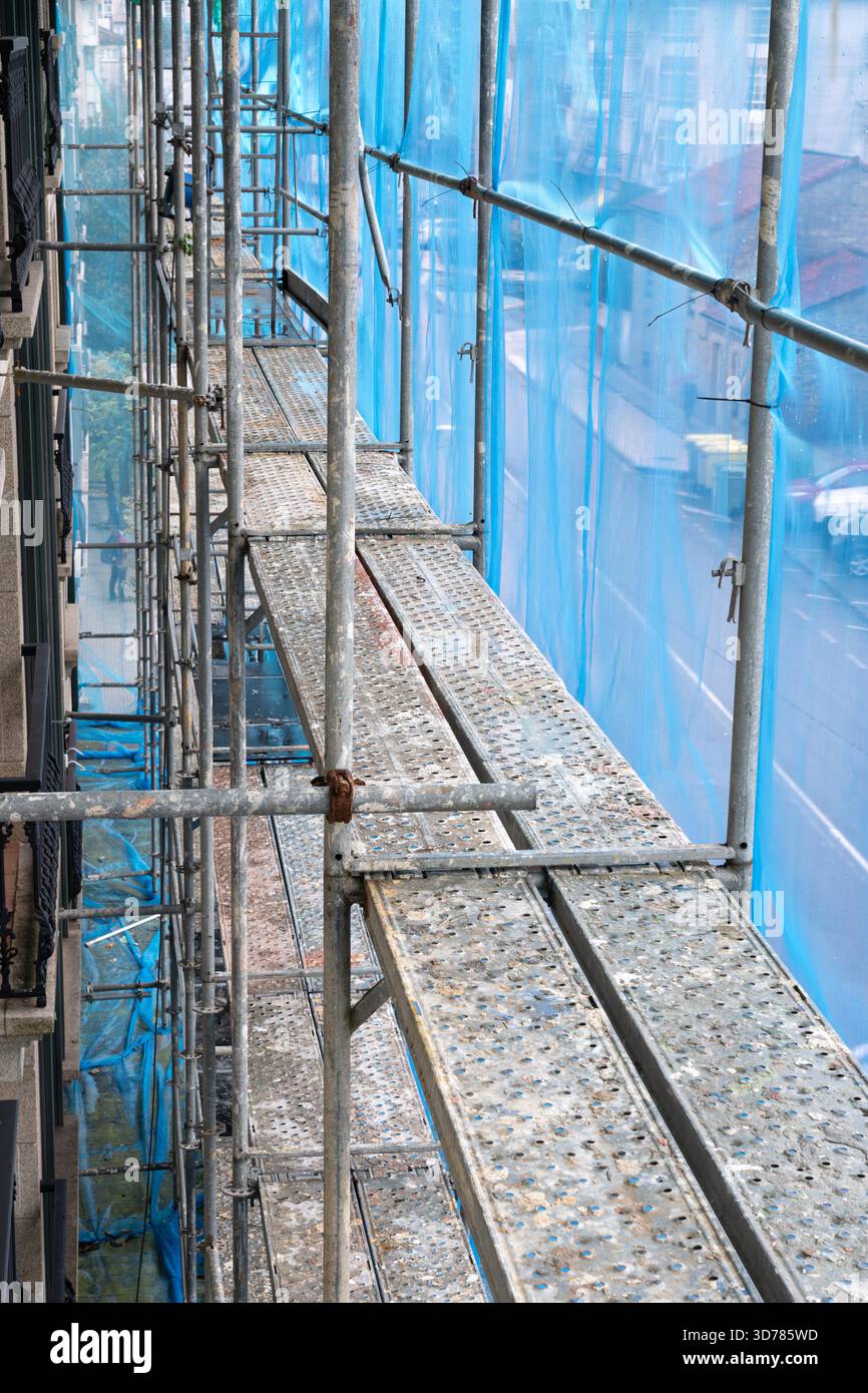 Scaffolding structure providing temporary access with platforms and protective netting for a building renovation project Stock Photo