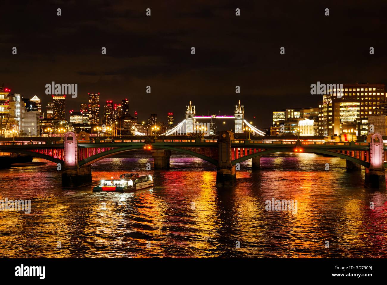 Brightly lit night time view along the River Thames with Southwark and Tower Bridge crossing the river, London, England. Stock Photo