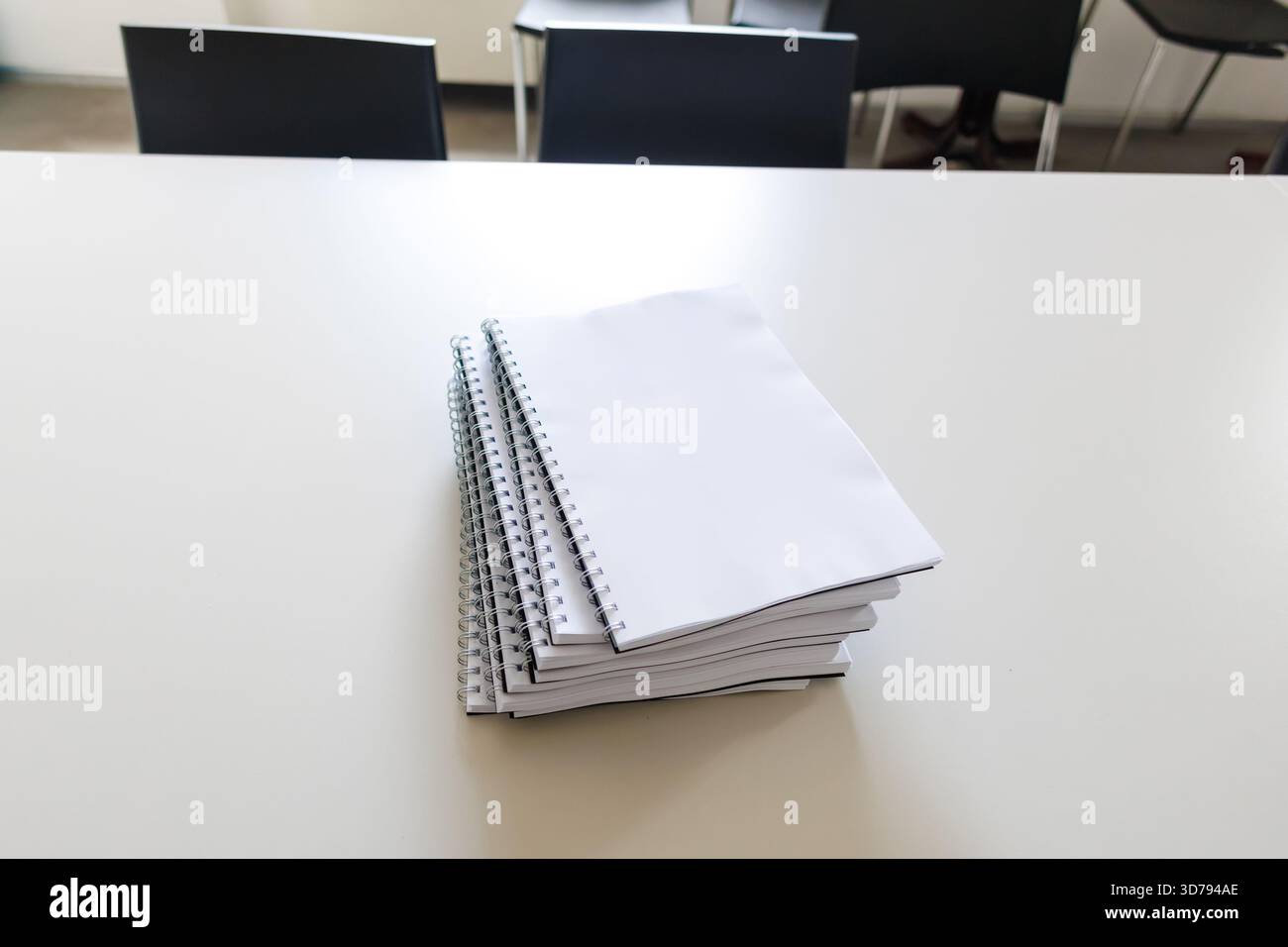 stack of blank spiral notebooks on a classroom table ready for student use during lessons Stock Photo