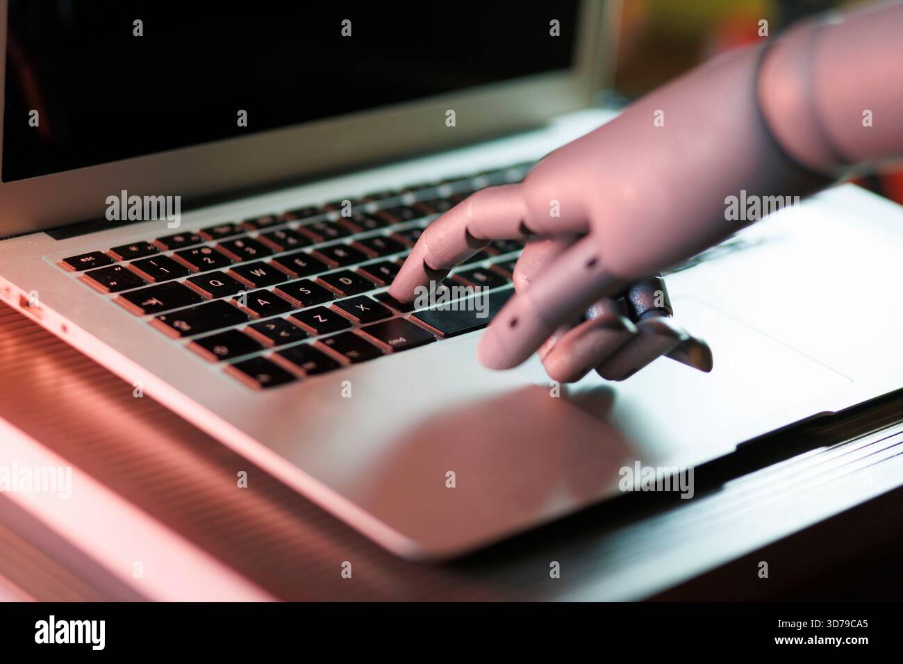 Robot hand interacting with laptop keyboard Stock Photo