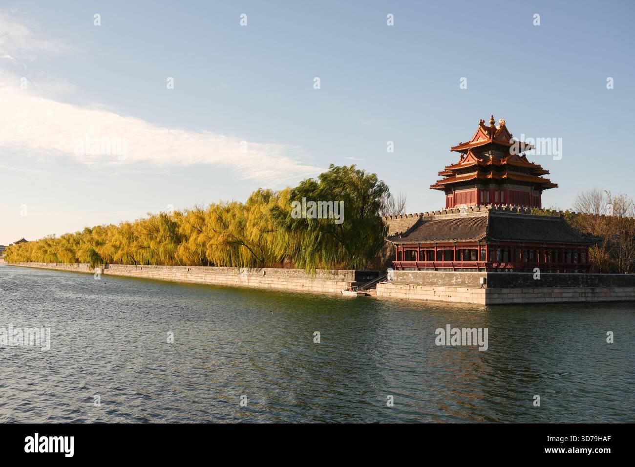 View of the Forbidden City's tranquil moat reflecting the ancient walls and golden foliage under a clear sky, Beijing, Beijing, China. Stock Photo