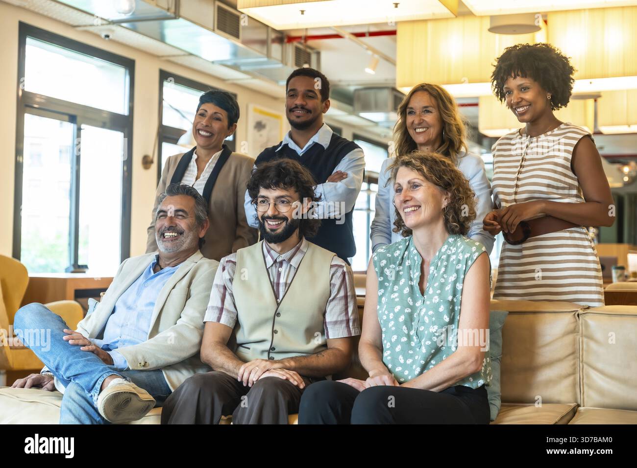 Diverse group of smiling coworkers in a modern coworking office, posing ...