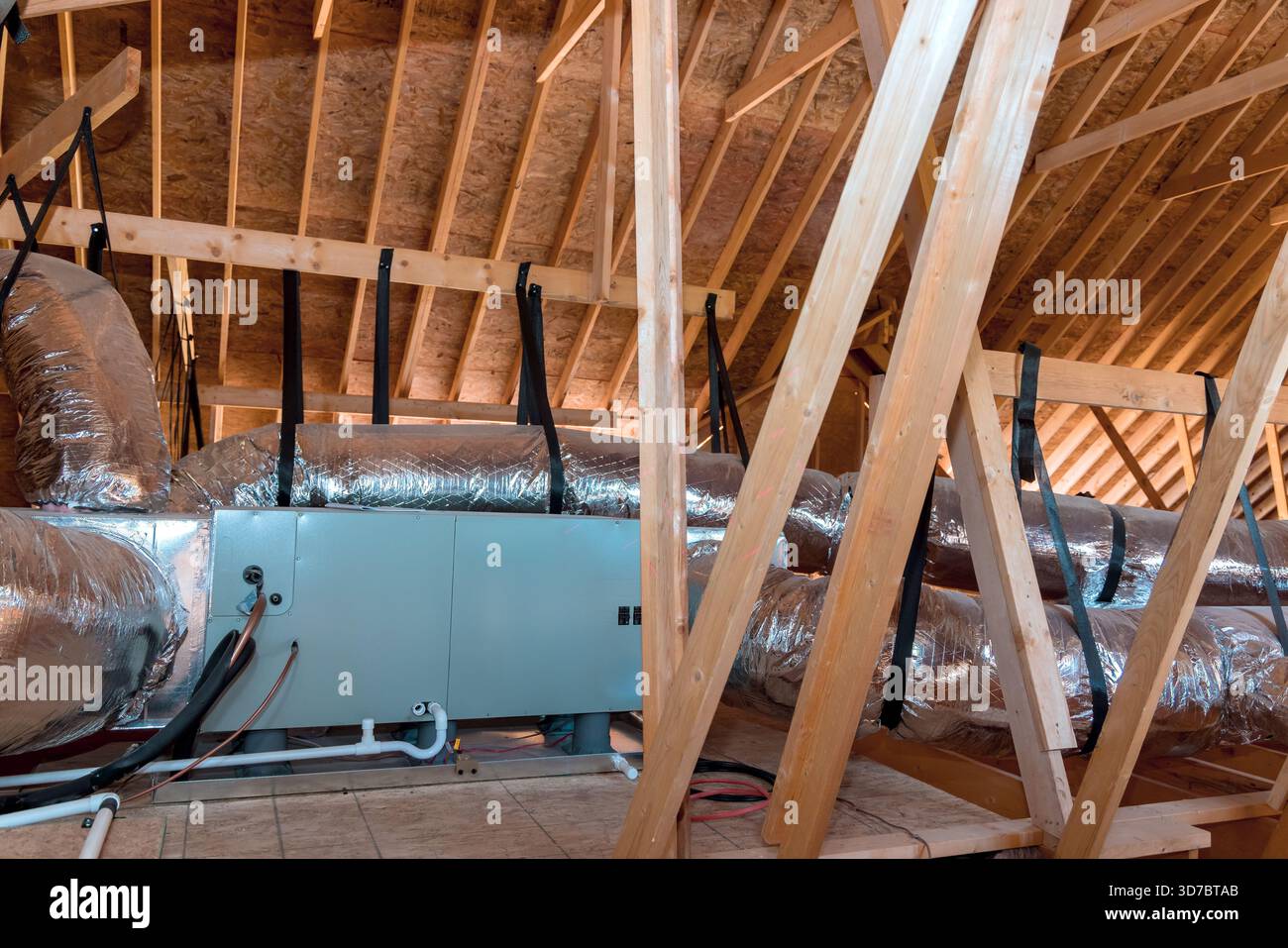 Workers are installing ductwork insulation in attic area of home during renovation. Stock Photo