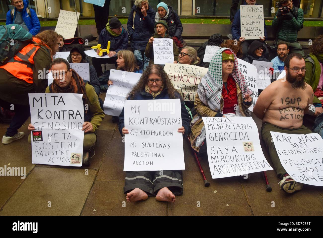 Protesters sit with a placard stating 'I oppose genocide, I support ...