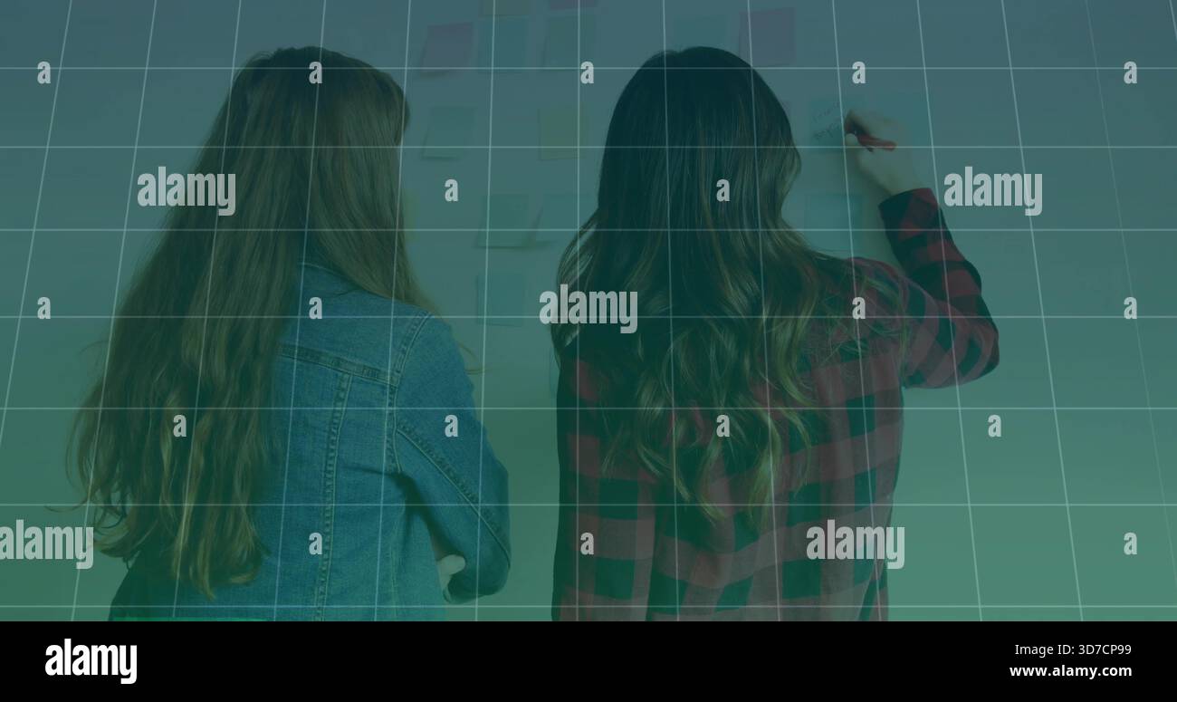 Writing two women working in classroom, marking wall with marker, denim jacket, plaid shirt, grid Stock Photo