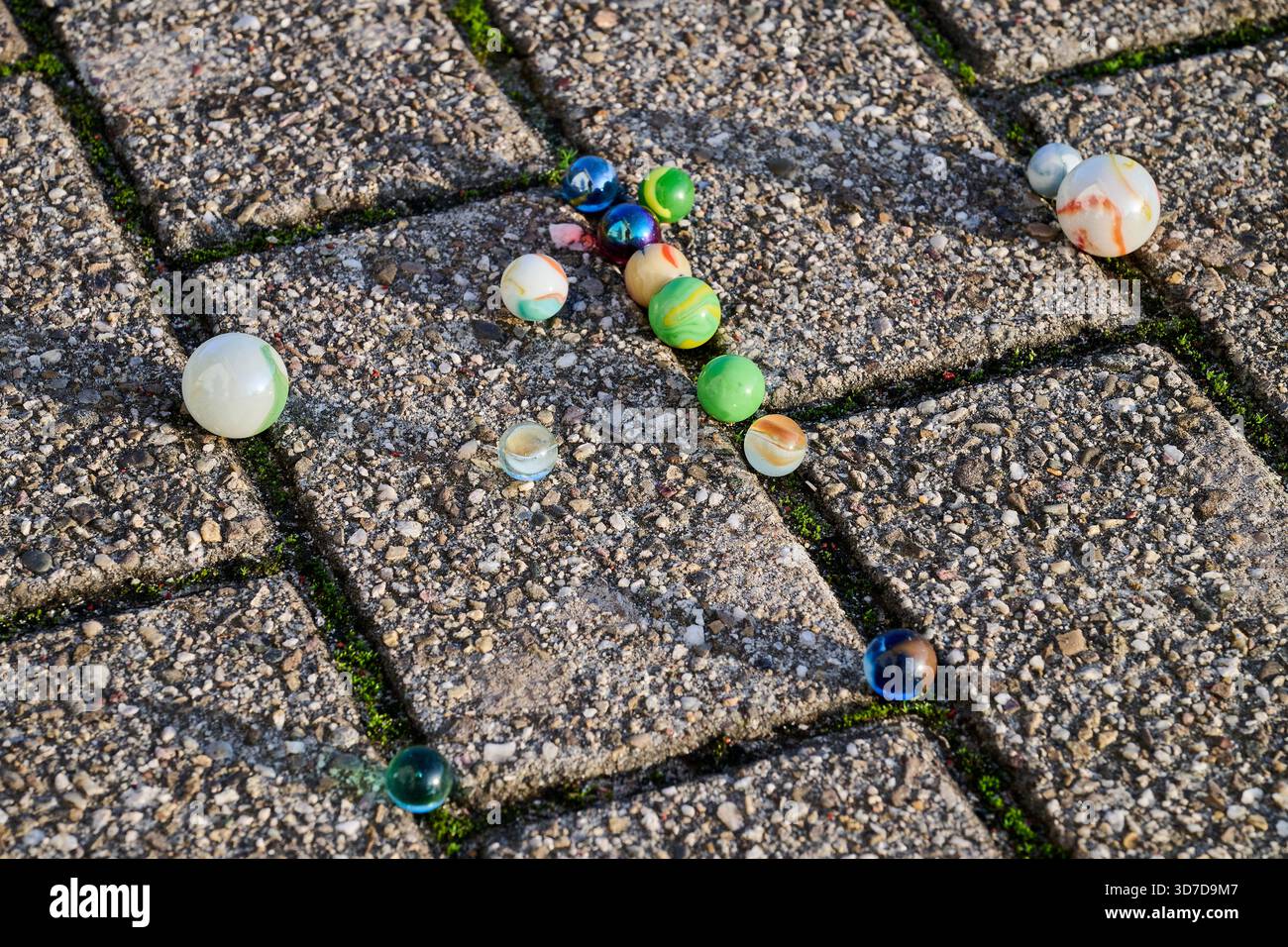 Colored marbles on a paved floor Stock Photo