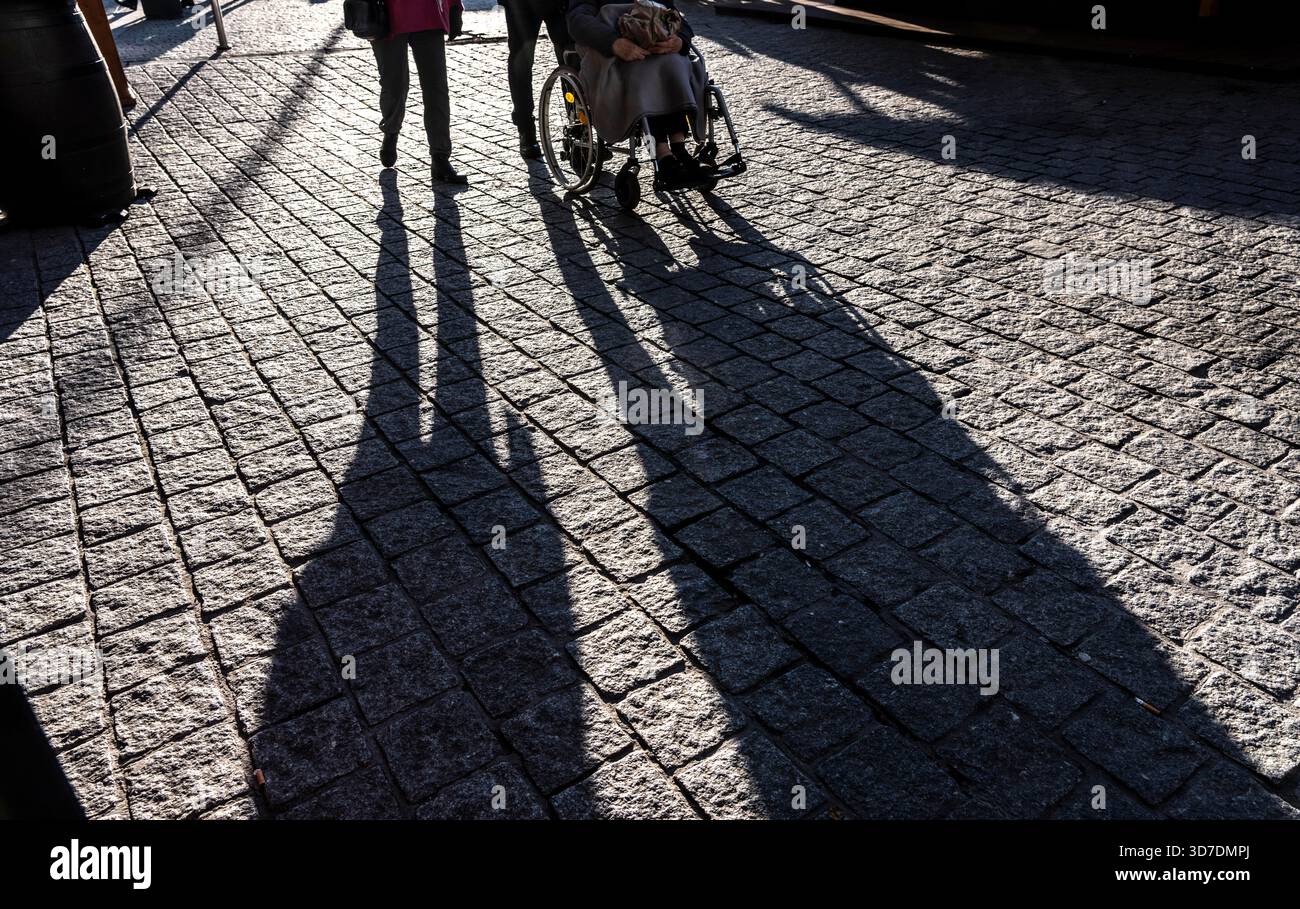 Shadows of people on the ground, low sun, winter, silhouettes, elderly person in wheelchair, Germany Stock Photo