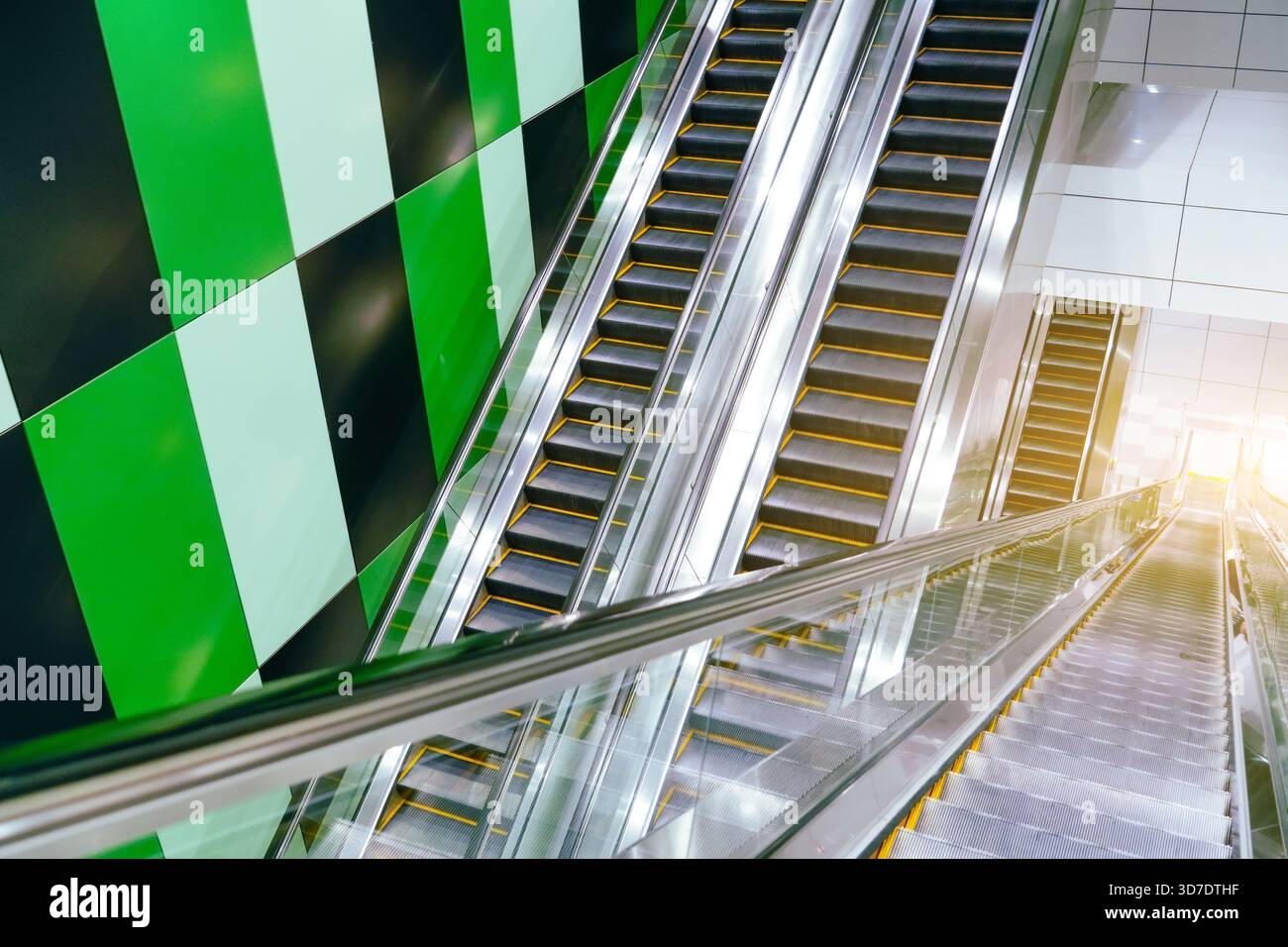 A set of escalators descends in a busy urban space, featuring a ...