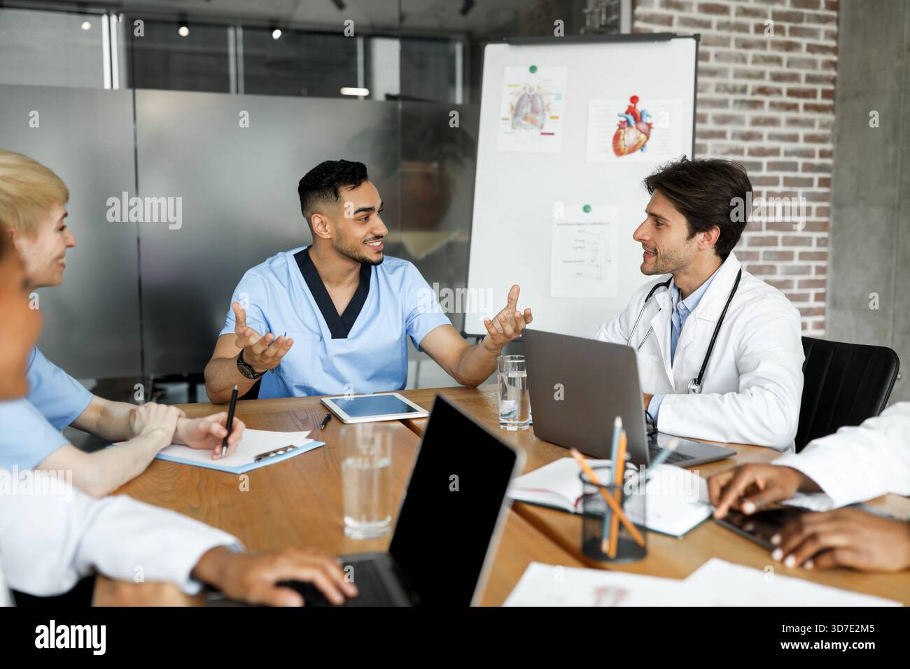 Cheerful multiracial doctors having conversation, using gadgets Stock Photo