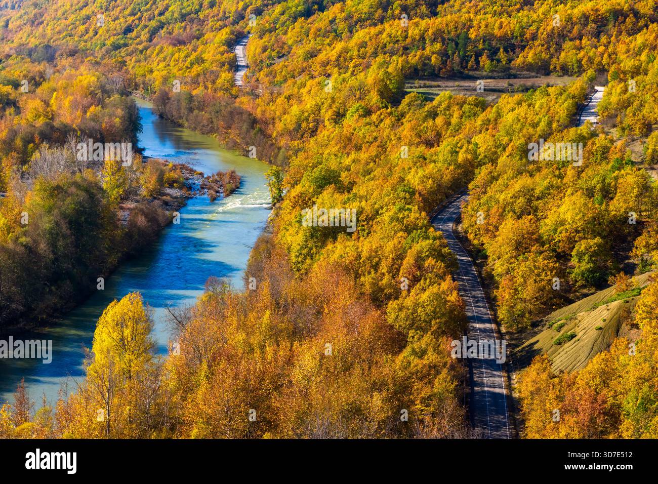 Aerial view of Venetikos River curving through vibrant autumn forest in ...