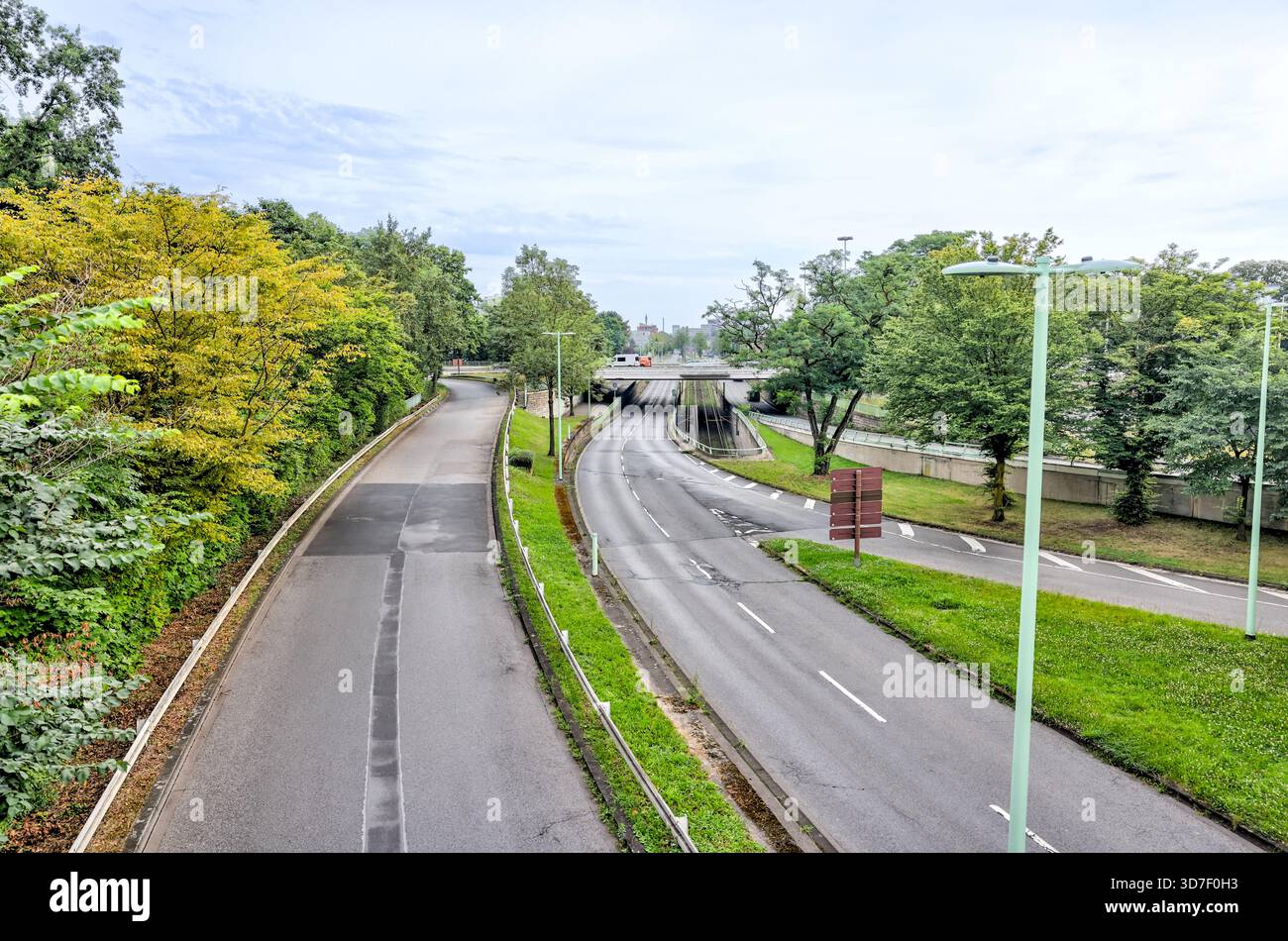 Curved multilane roadway surrounded by dense greenery and parks on the outskirts of Cologne, Germany. Stock Photo