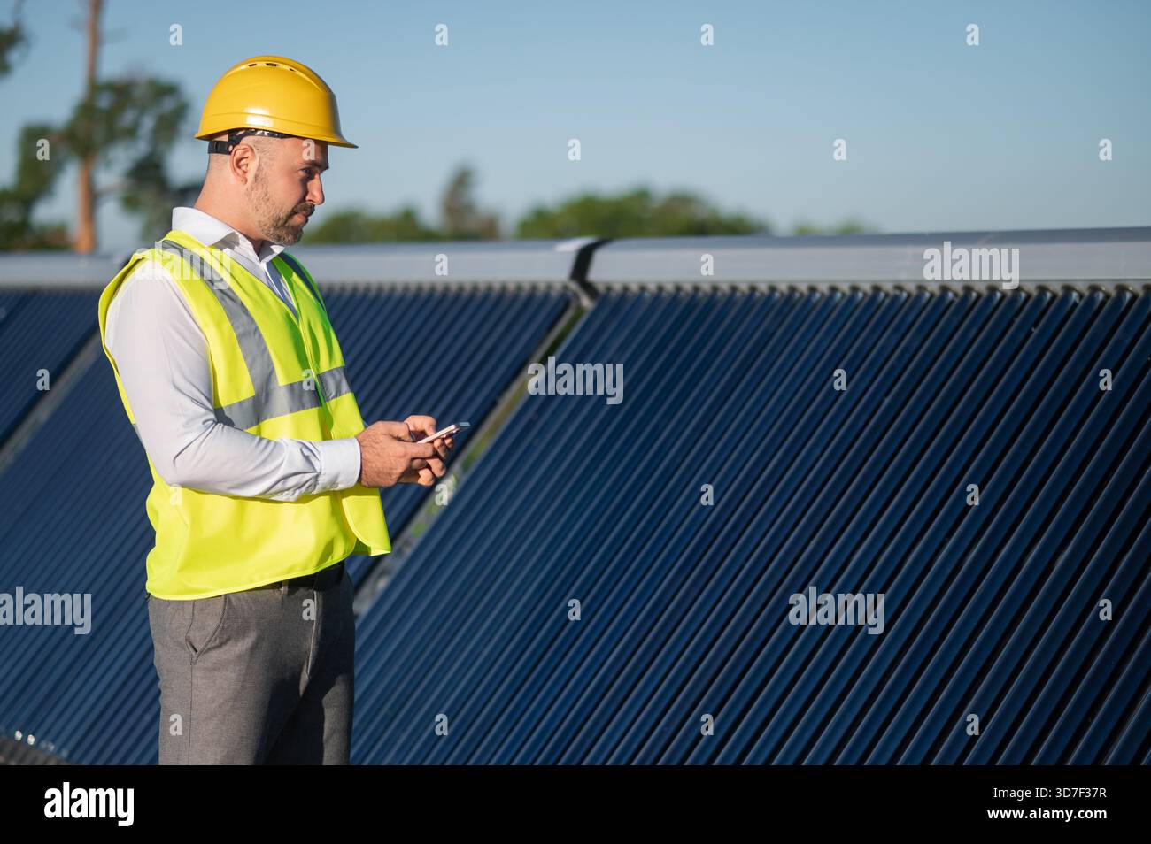 Unrecognizable technician checking data on phone while standing by solar installation Stock Photo