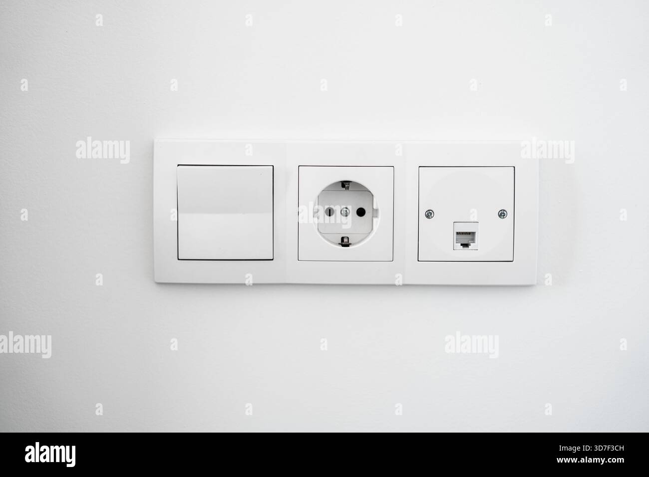 Modern white wall switch and electrical socket panel installed on clean ...
