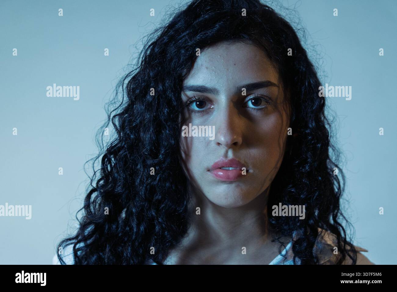 Young woman with curly hair and serious expression looking at camera Stock Photo