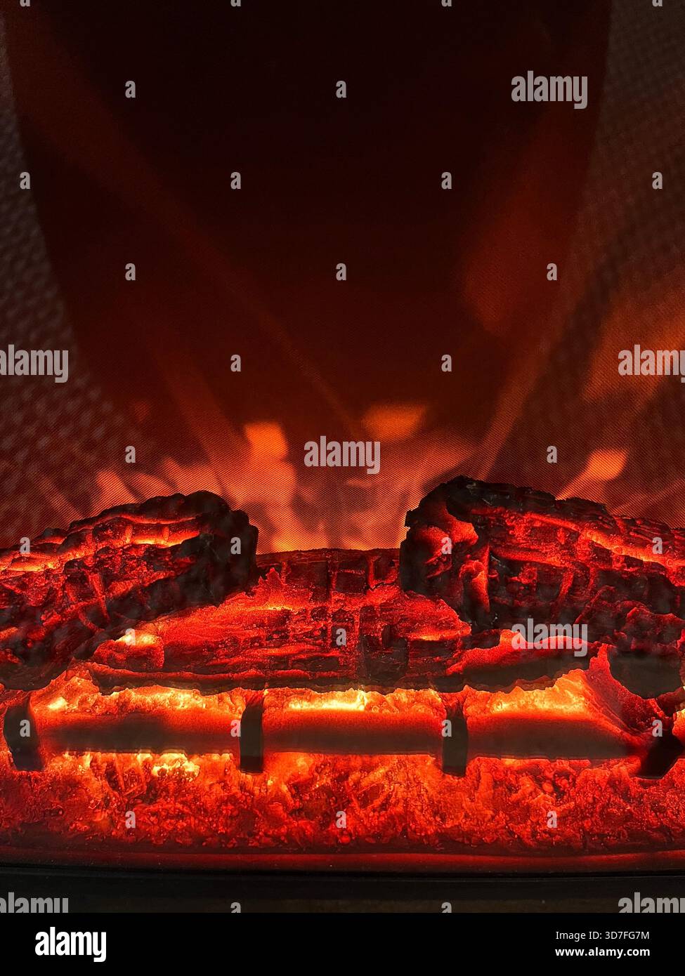Realistic Artificial Fireplace Logs with Glowing Flames Creating a Warm Cozy Atmosphere Indoors - Smartphone Captured Stock Image