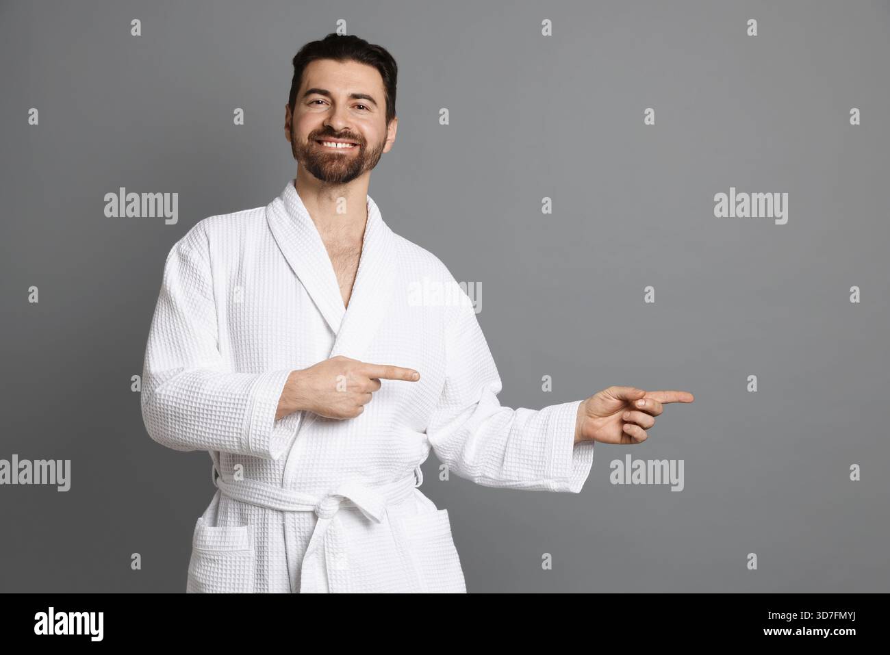 Man in bathrobe pointing at something on grey background Stock Photo