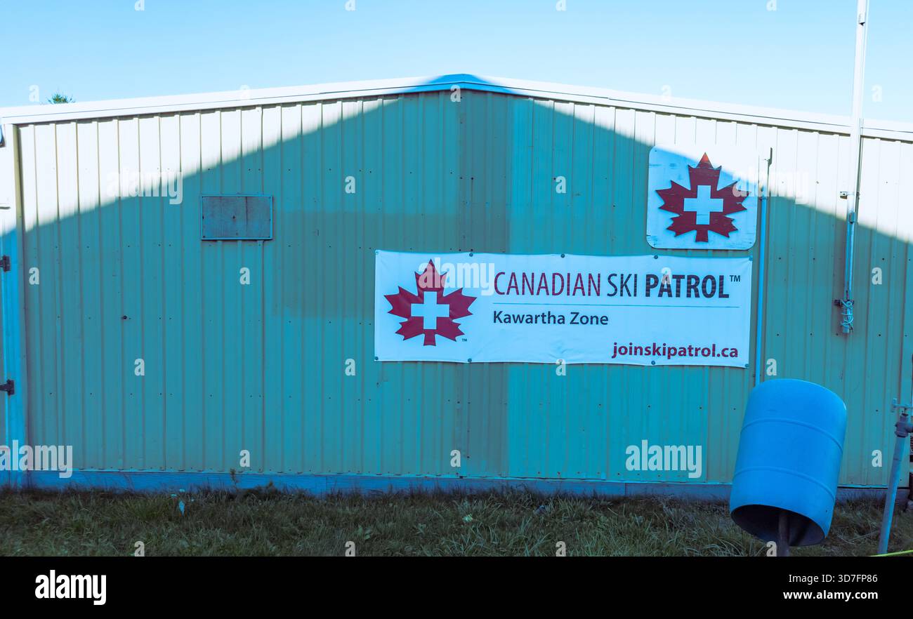 Durham Region, On Canadian Ski Patrol Kawartha Zone sign on green building exterior with barrel and rope in foreground. - Smartphone Captured Stock Image