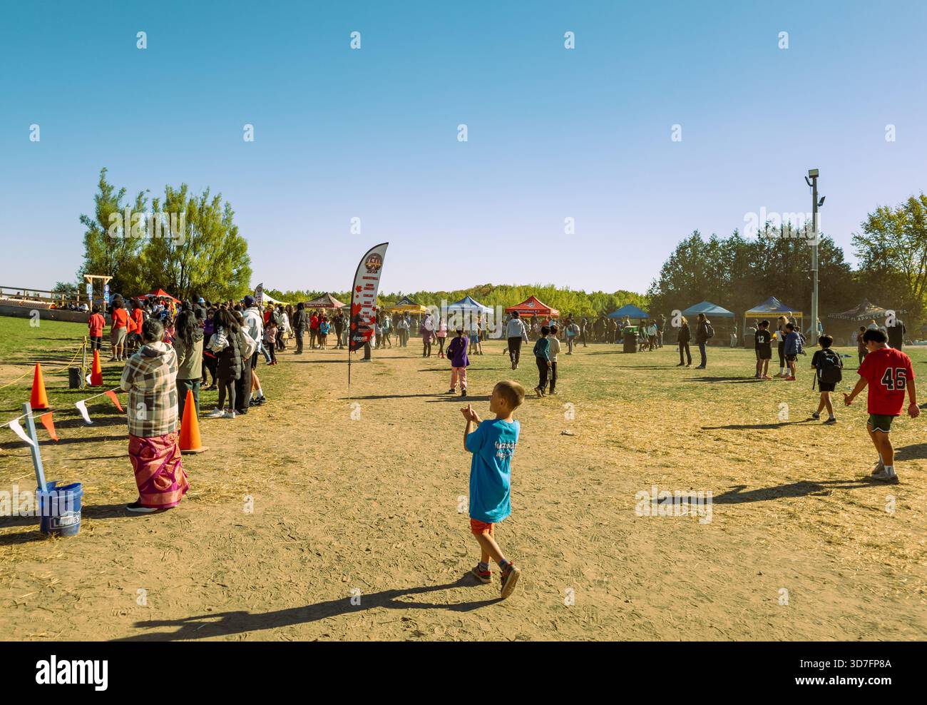 Lakeridge area of Durham Region, Ontario, Canada 10-9-2025 Runners in red shirts ascend grassy hill during organized race with cones and spectators - Smartphone Captured Stock Image