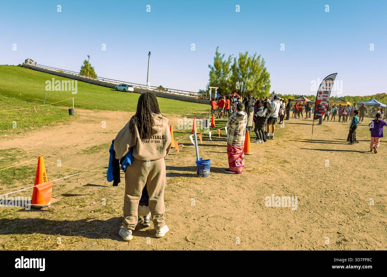 Lakeridge area of Durham Region, Ontario, Canada 10-9-2025 Runners in red shirts ascend grassy hill during organized race with cones and spectators - Smartphone Captured Stock Image