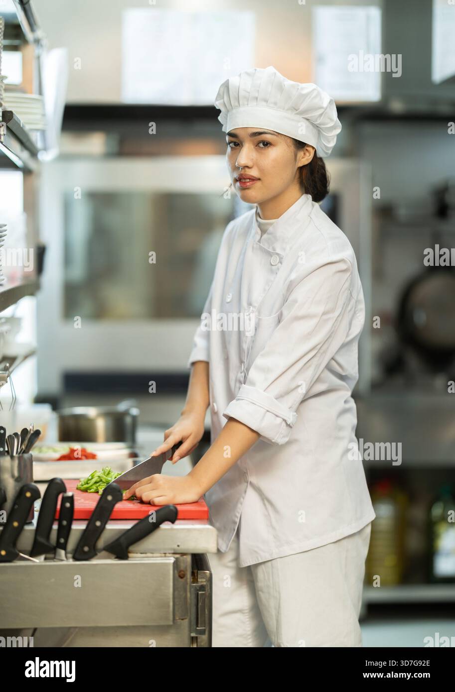 Young female chef chops ingredients for dish Stock Photo