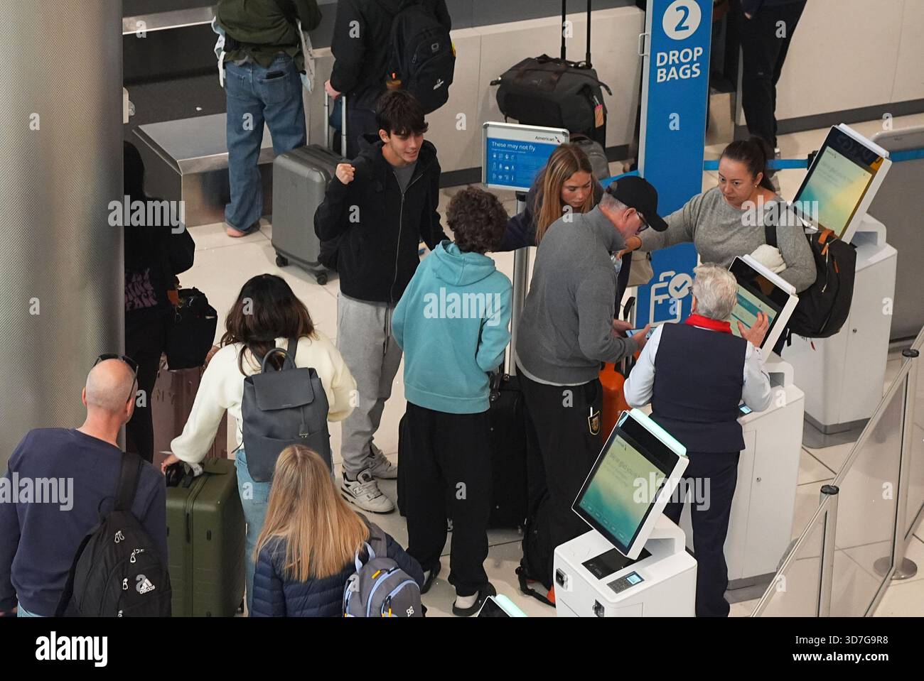 Travelers queue up to check in at the ticketing counter for American ...