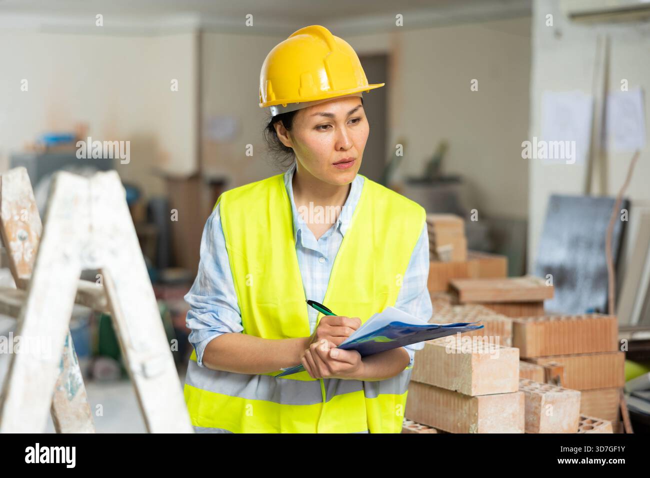 Woman making notes on indoor construction site Stock Photo