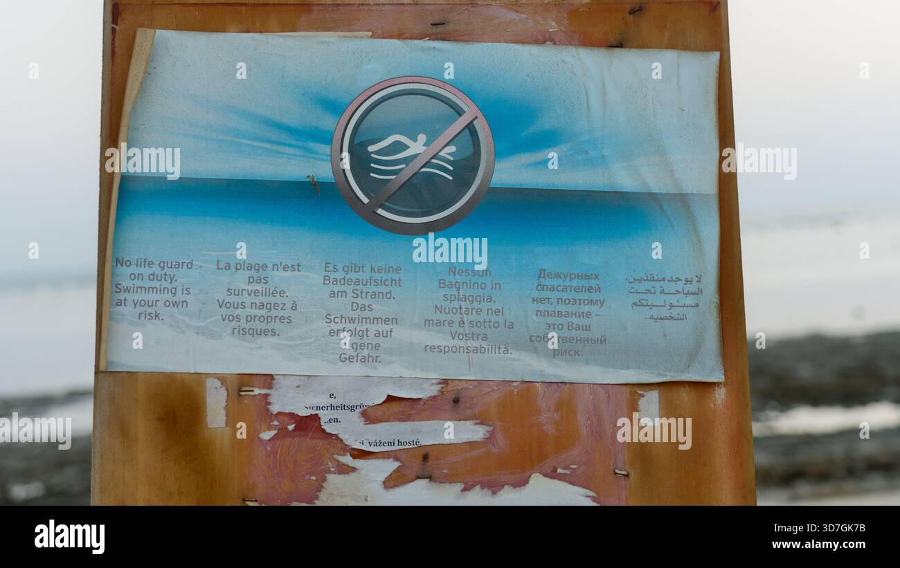Multilingual Help Sign A multilingual warning sign reading “bathing at your own risk” stands ...
